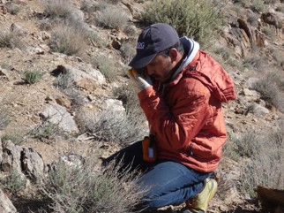 PROGREM geologist examining an outcrop with a hand lens